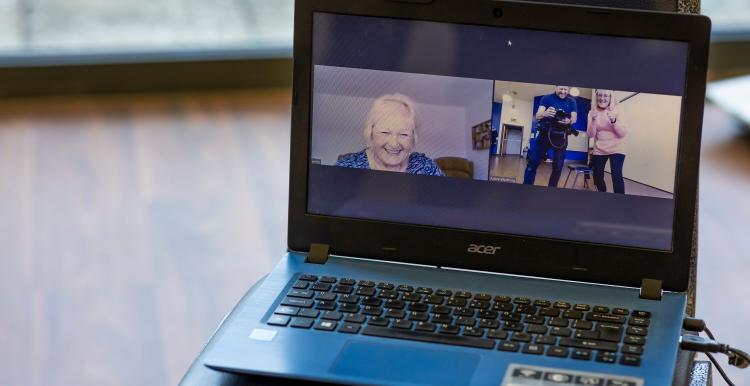 A laptop showing three people on a video call