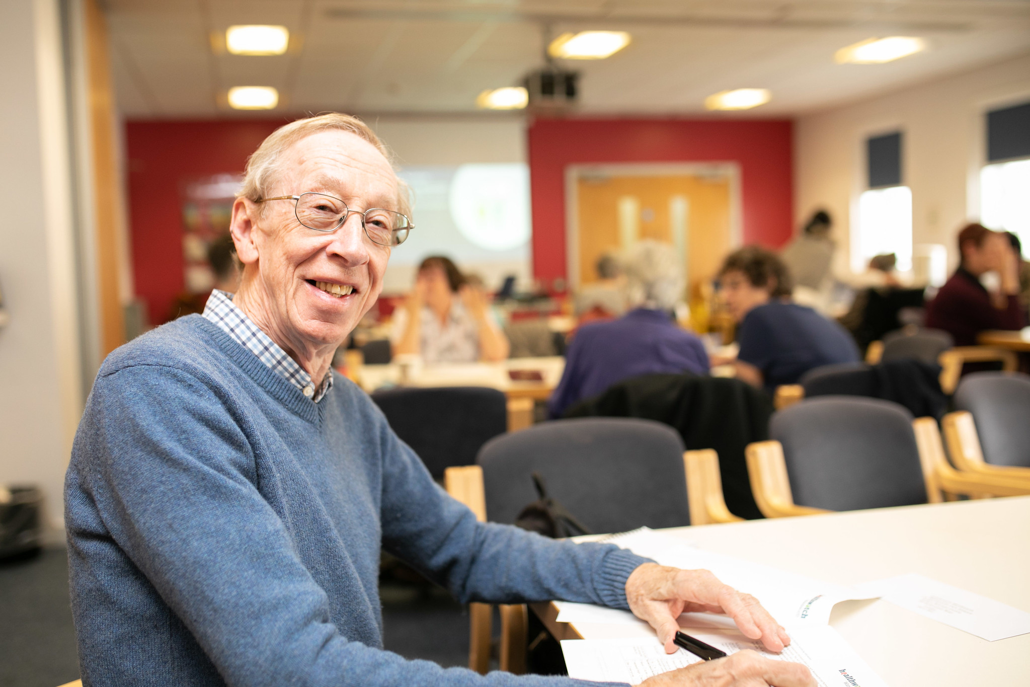 Gentleman sat at a table in a busy meeting room