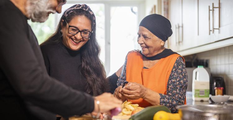 Older Sikh couple receiving help and support while cooking.