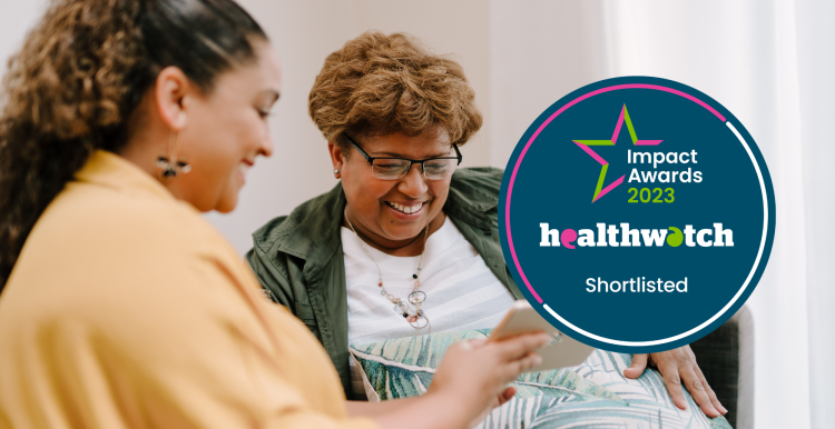 Two people sitting on a sofa, looking at a tablet. Over the image is a dark blue roundel. White, pink and green text on the roundel reads: 'Impact Awards 2023' - 'Healthwatch' - 'Shortlisted'
