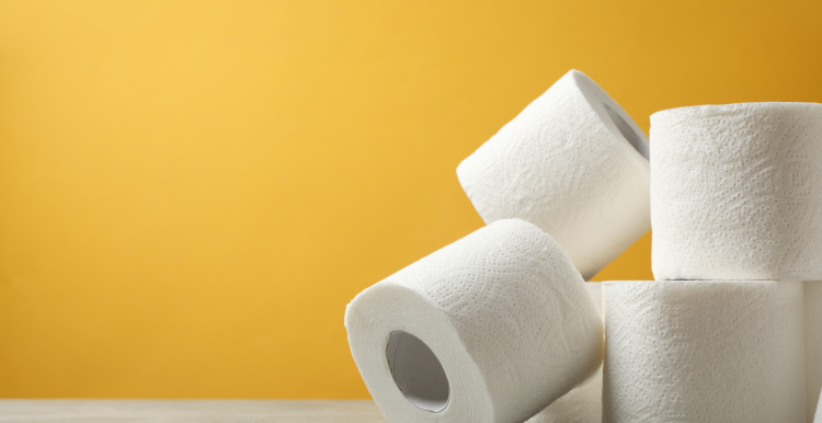 Four rolls of toilet paper stacked against a yellow background.
