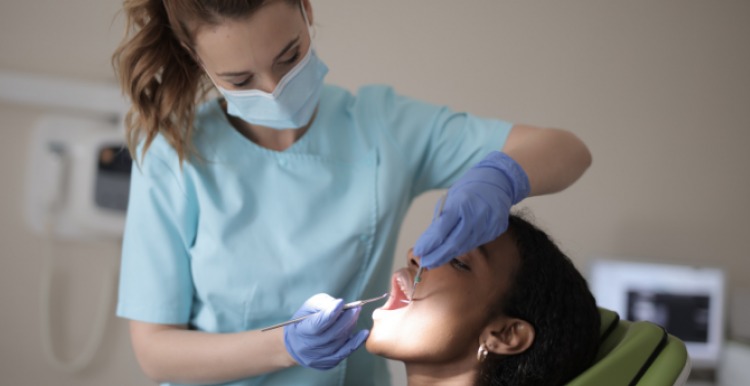 A person sitting in a dentist's chair, having dental work done by a dentist.