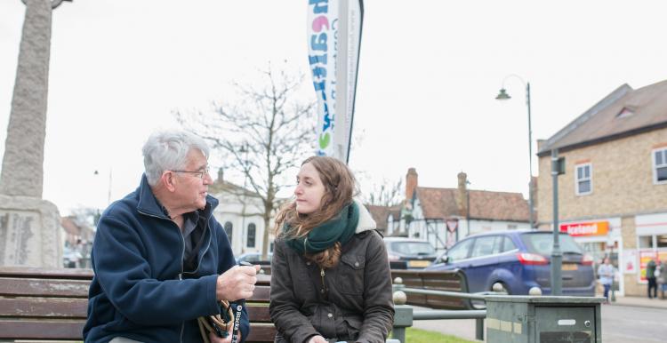 Elderly man and young woman sitting on a bench