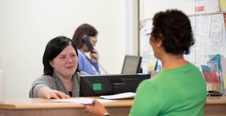 Woman stood a reception talking to the girl behind the desk