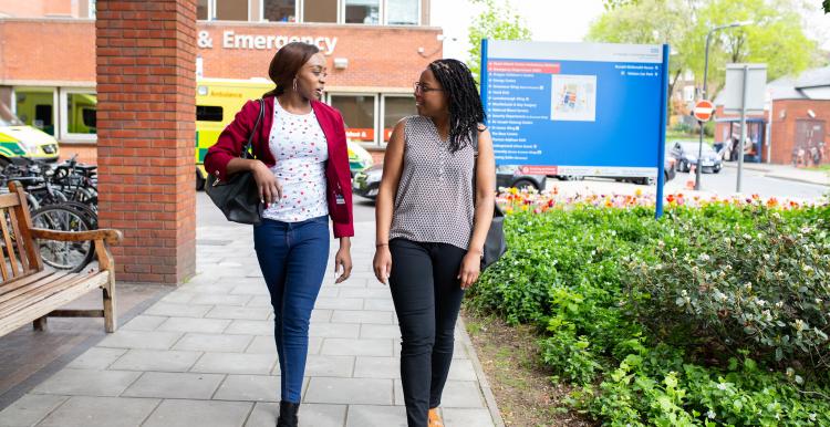 Two women walking into a hospital together