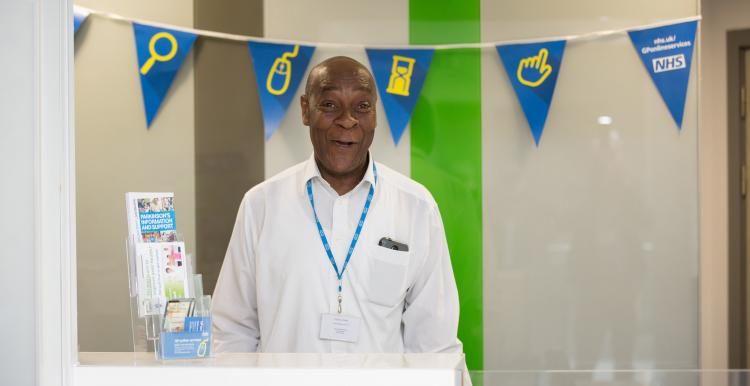Man in the NHS standing behind a reception desk
