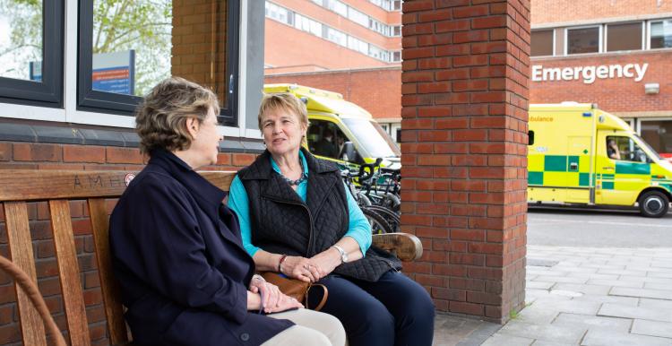 Two women sat talking outside a doctors surgery