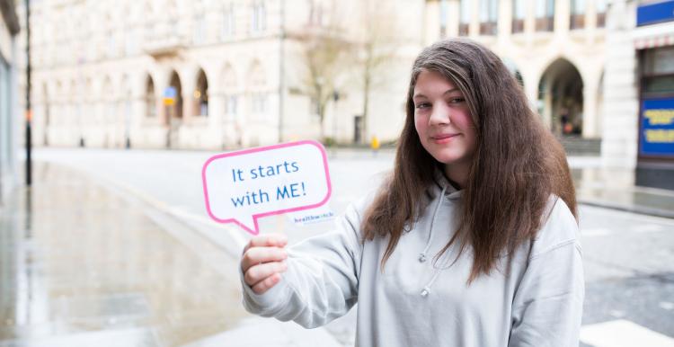 Young girl holding a sign "It starts with me"