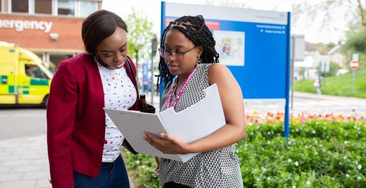 Two women looking at a report outside the hospital