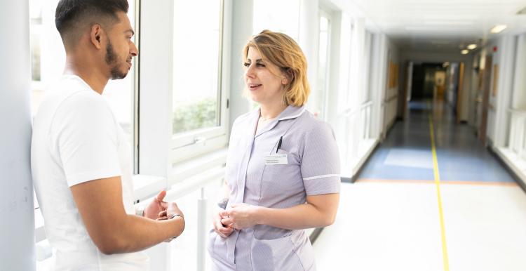 Man talking to nurse in hospital corridor