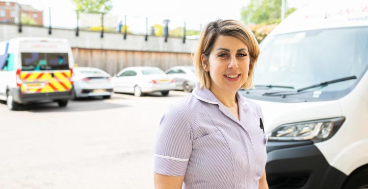 Woman standing in front of a hospital transport bus