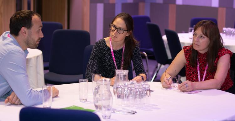 Three adults sat round a table having a discussion