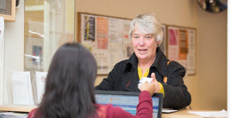 Lady talking to a female receptionist sat behind her desk