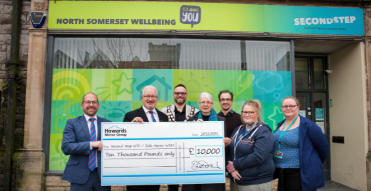 A group of people standing outside the Safe Haven Crisis Centre. They are holding a large cheque from Howards Motor Group for £10,000