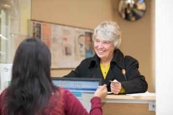 Lady talking to a female receptionist sat behind her d