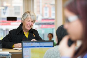 Woman stood a reception talking to the girl behind the desk