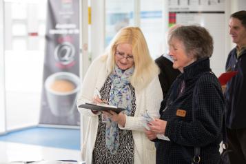 Doctor wearing a white coat speaking to a patient