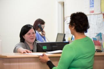 Woman stood a reception talking to the girl behind the desk