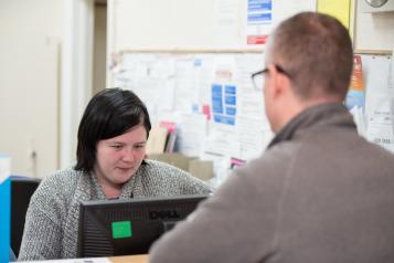 Man booking an appointment at the reception desk of his local GP surgery