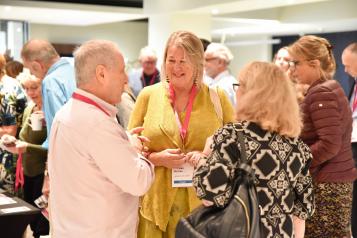 Women wearing Healthwatch badges talking together at an event