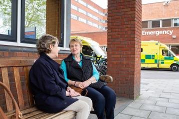 Two women sat talking outside a doctors surgery