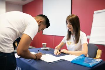 Man filling out a form by a woman sitting at a desk