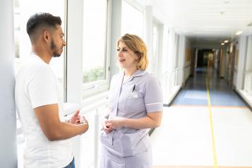 Man talking to nurse in hospital corridor