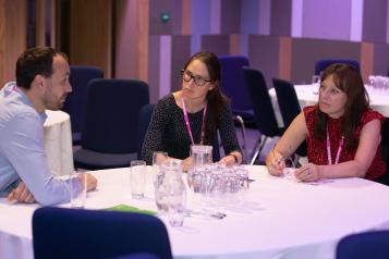 Man and two women sitting round a table talking