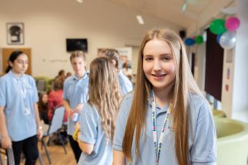 Young girl sitting on her own in a room full of peers