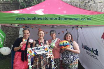 Healthwatch staff standing in front of their stand at the pride event