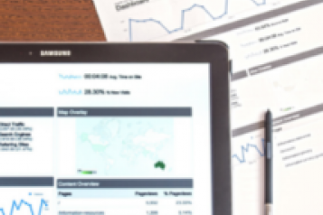 A laptop and sheets of paper showing bar graphs