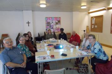 volunteers sat round the table listening to a speech
