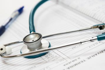 A stethoscope and a blue ball point pen on top of a form