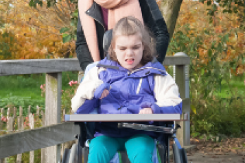 A woman pushing a young girl in a wheelchair