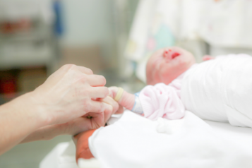 Photo of someone holding the hand of a newborn baby