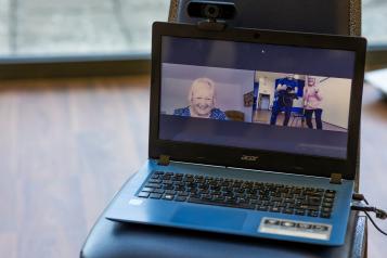 A laptop showing three people on a video call
