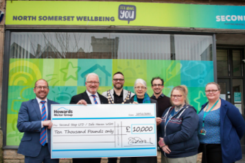 A group of people standing outside the Safe Haven Crisis Centre. They are holding a large cheque from Howards Motor Group for £10,000