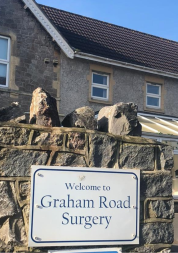 A 'Welcome to Graham Road Surgery' sign with the surgery in the background